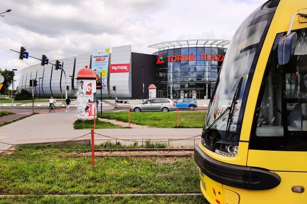 Żółty tramwaj na zielonym torowisku w Toruniu